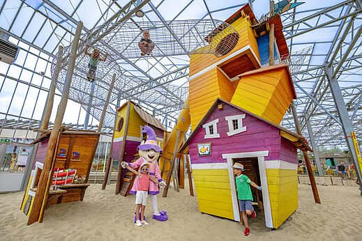 Zona de juegos interior con redes, casitas de colores y arena en el camping CAPFUN Vakantiepark Capfun het Stoetenslagh en Rheezerveen.