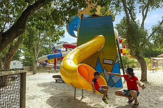 Niño en tobogán amarillo área de juegos arena en el camping CAPFUN Sud Land en Labenne-Ocean (40).