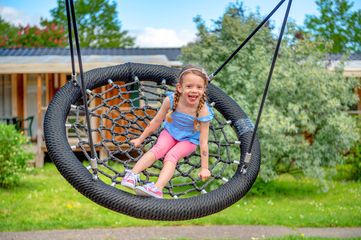 Niña sonriente en un columpio nido de pájaro en el camping CAPFUN Suzel en Sainte-Croix-en-Plaine (68).