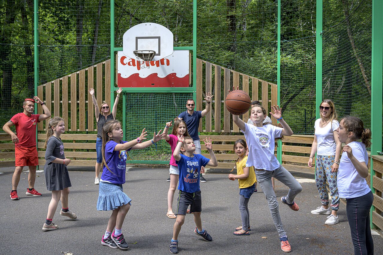 Cancha de baloncesto con ni�os y adultos jugando en el camping CAPFUN Talaris Vacances en Lacanau (33).
