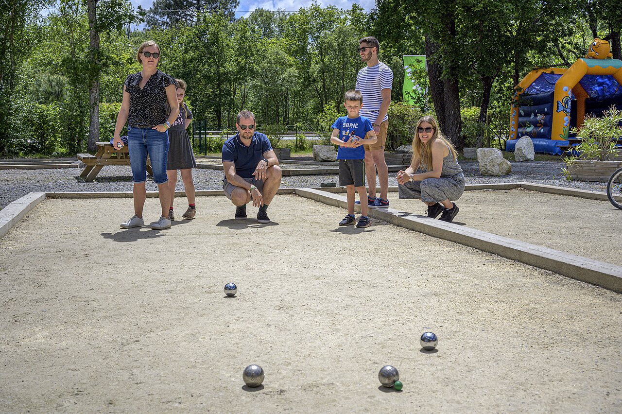 Familia jugando a la petanca en una cancha dedicada en el camping CAPFUN Talaris Vacances en Lacanau (33).