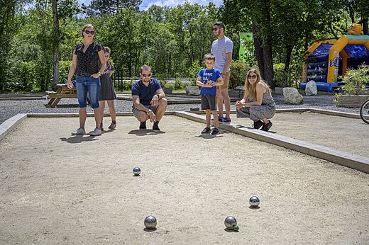 Familia jugando a la petanca en la cancha del camping CAPFUN Talaris Vacances.