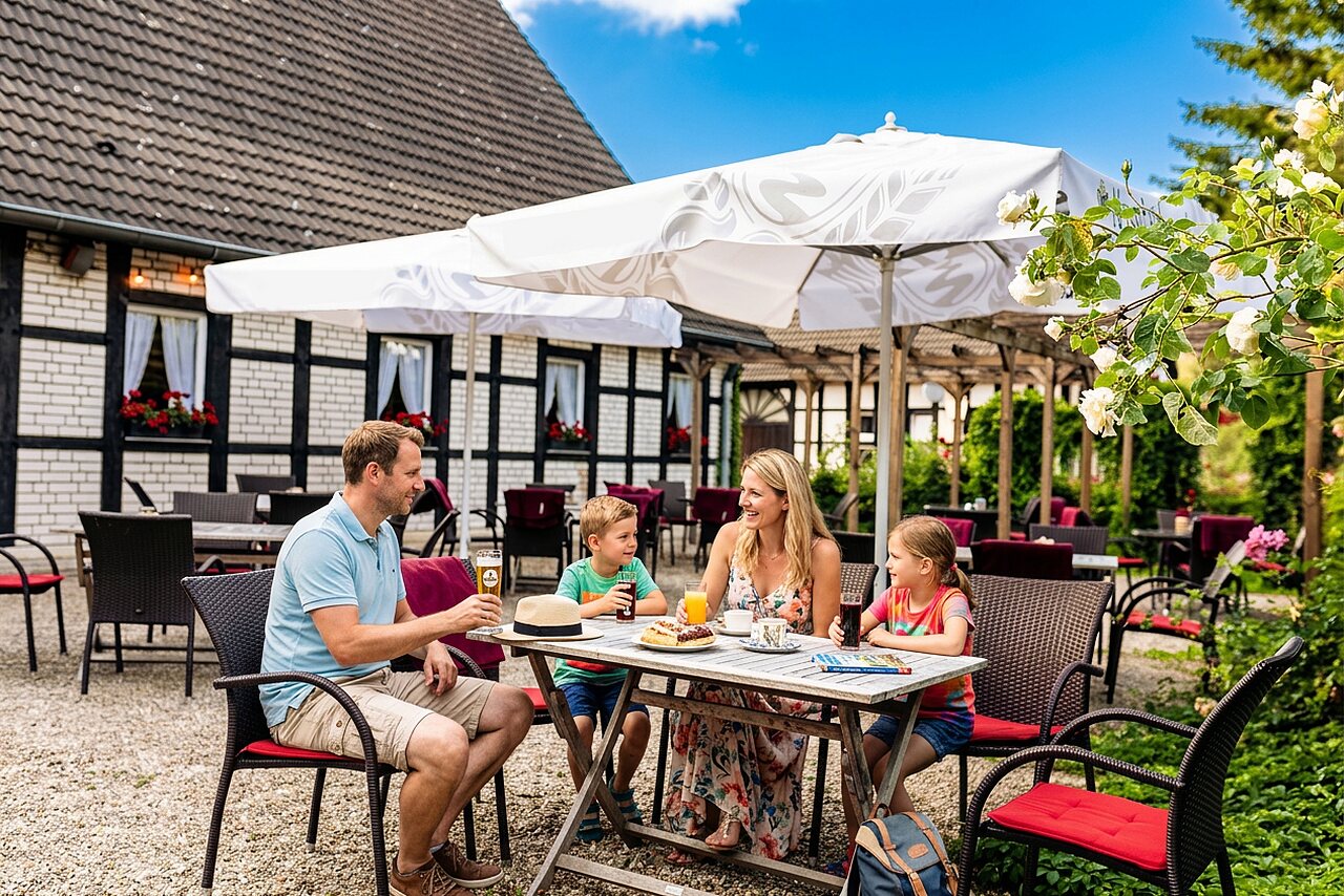 Familia almorzando en la terraza del restaurante exterior en el camping CAPFUN Tecklenburg en Tecklenburg-Leeden (49).