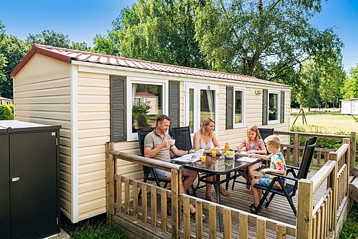 Familia desayunando en la terraza de una Mobil-home en el camping CAPFUN Tecklenburg.