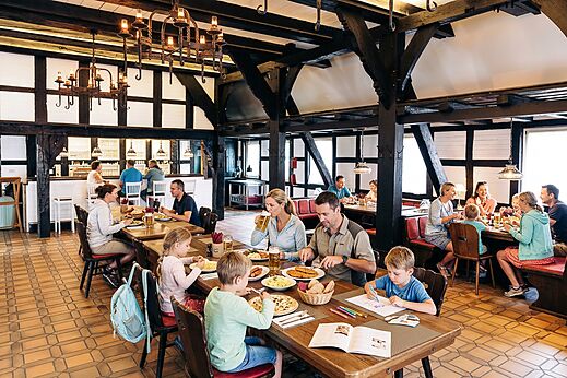 Familias y parejas cenando en el restaurante r�stico del camping CAPFUN Tecklenburg en Tecklenburg-Leeden (49).