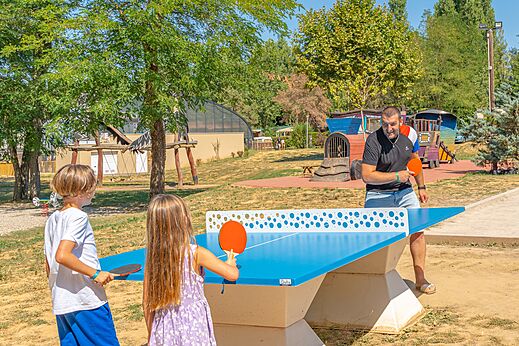 Familia jugando al ping-pong exterior en el camping CAPFUN Temps Libre en BOUGE CHAMBALUD.