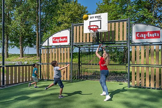 Campo multideporte con canasta de baloncesto, familia en camping CAPFUN Tensch Jolie.