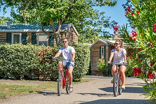 Pareja en bicicleta por un camino del camping CAPFUN Teorix en MARSEILLAN PLAGE (34).