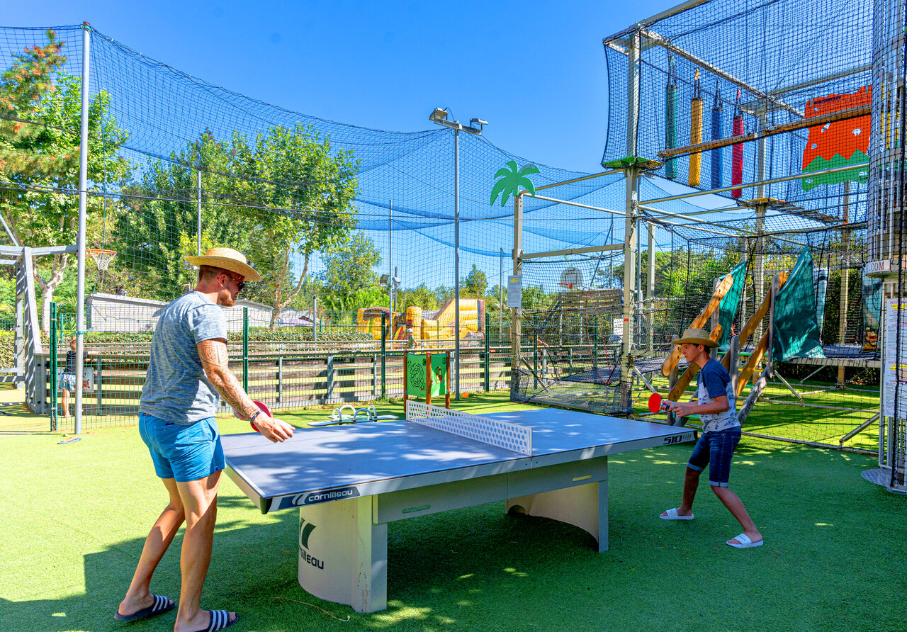 Padre e hijo jugando al ping-pong en c�sped artificial en camping CLICOCHIC Texas en Argel�s sur Mer (66).