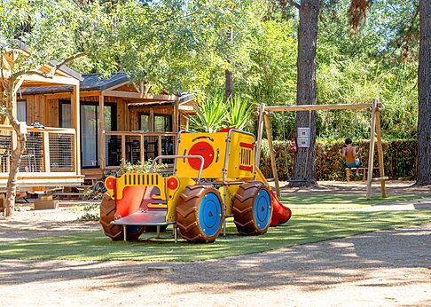 Zona de juegos infantil con tractor y columpio cerca de los Mobil-homes en el camping CLICOCHIC Texas en Argelès sur Mer (66).