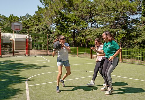 Mujeres jugando baloncesto en cancha multideporte en el camping CLICOCHIC Plage des Tonnelles en Saint-Jean-de-Monts (85).
