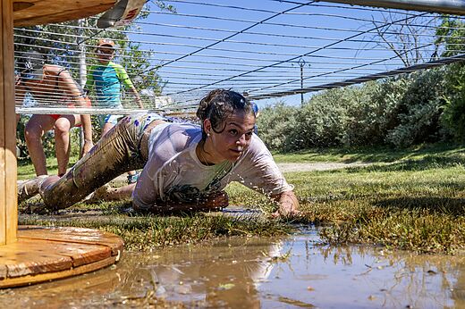 Carrera de obst�culos con barro, persona arrastr�ndose en camping CAPFUN Tordera-Nacions en Malgrat de Mar.