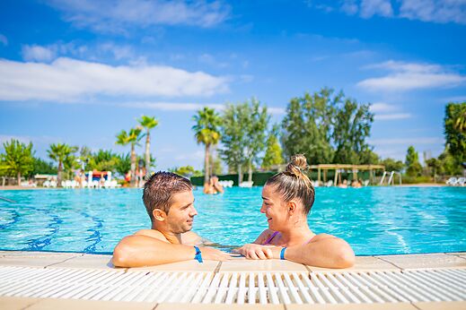 Pareja sonriente en la piscina exterior del camping CAPFUN Tordera-Nacions en Malgrat de Mar.