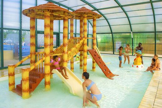 Espacio acuático cubierto con juegos y toboganes en el camping CAPFUN Celeste en Breuillet (17).