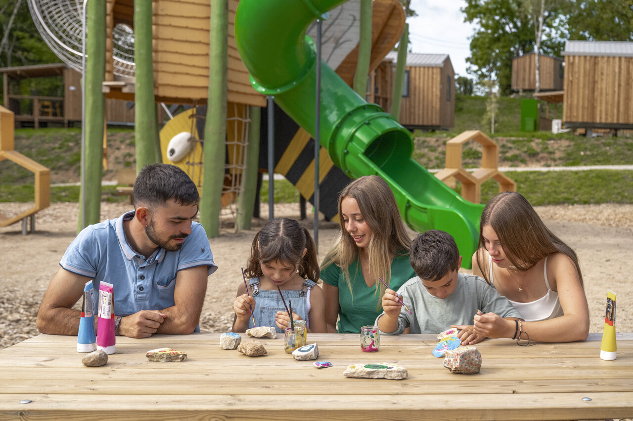 Familia pintando rocas, zona de juegos tobog�n en el camping CLICOCHIC Trelachaume en Maisod (39).