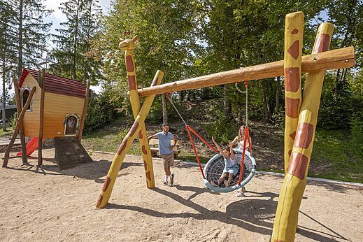Zona de juegos con columpio nido y casita, camping CLICOCHIC Trelachaume en Maisod (39).