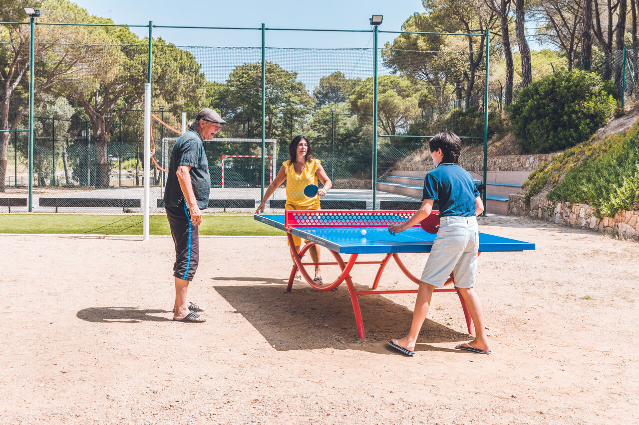 Familia jugando al ping-pong al aire libre en camping CAPFUN Treumal Platja d'Aro.