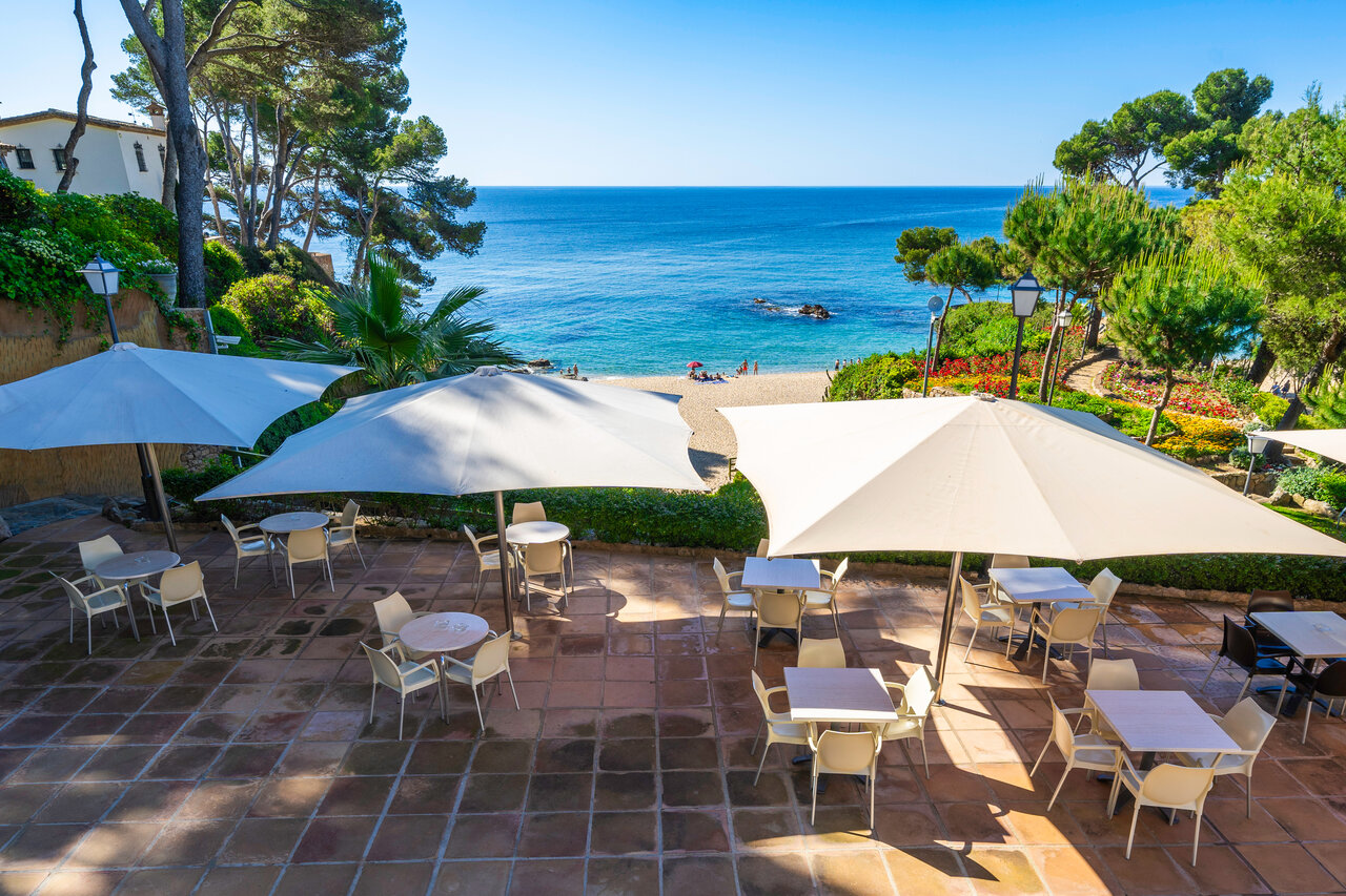 Terraza de restaurante con sombrillas, playa y mar Mediterr�neo en el camping CAPFUN Treumal en Platja d'Aro (17).