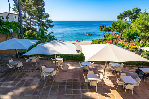 Terraza restaurante, mesas, sombrillas, mar en el camping CAPFUN Treumal en Platja d'Aro.