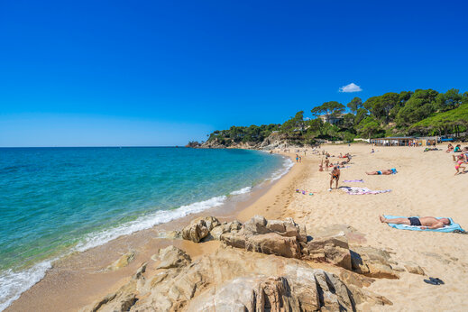 Playa de arena fina, mar turquesa y rocas en el camping CAPFUN Treumal.