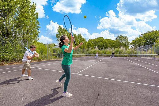 Cancha de tenis con personas jugando en el camping CLICOCHIC Trois Chênes en Pornichet (44).