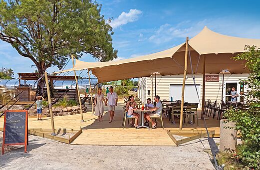 Terraza sombreada del restaurante y bar en camping CLICOCHIC Trois Chênes.