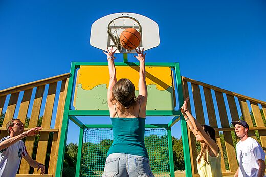 Jóvenes jugando baloncesto en la cancha del camping CLICOCHIC Trois Chênes en Pornichet (44).