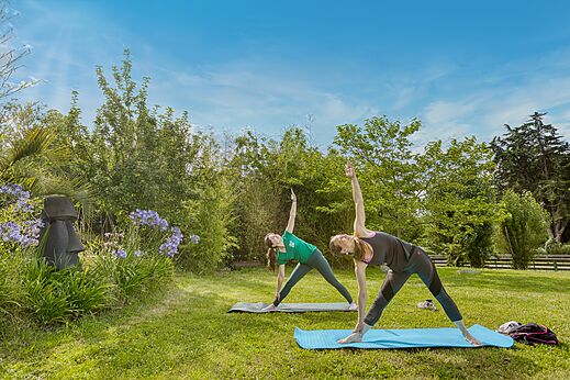 Dos mujeres practican yoga al aire libre en el camping CLICOCHIC Trois Chênes.