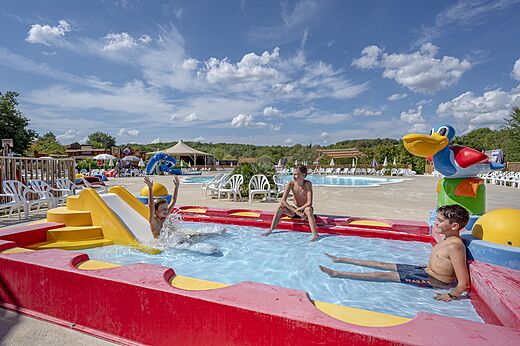 Ni�os jugando en la zona de juegos acu�ticos con tobog�n en el camping CAPFUN Ullule en Tournon d'Agenais (47).