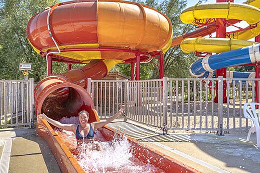 Mujer sonriente bajando por un tobogán acuático gigante en el camping CAPFUN Ullule en Tournon d'Agenais (47).