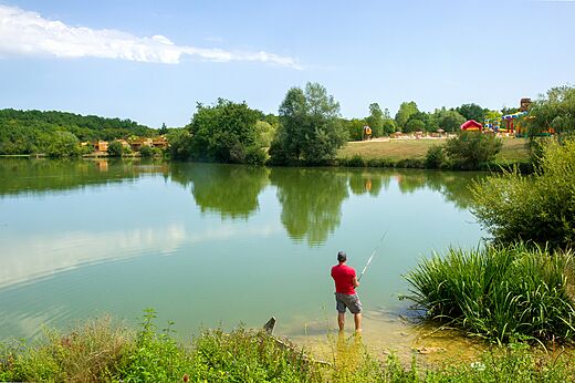 Hombre pescando tranquilamente en el lago del camping CAPFUN Ullule en Tournon d'Agenais (47).