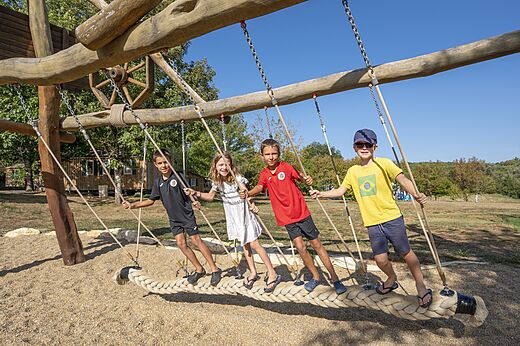 Niños sonrientes jugando en un gran columpio de cuerda en el camping CAPFUN Ullule en Tournon d'Agenais (47).