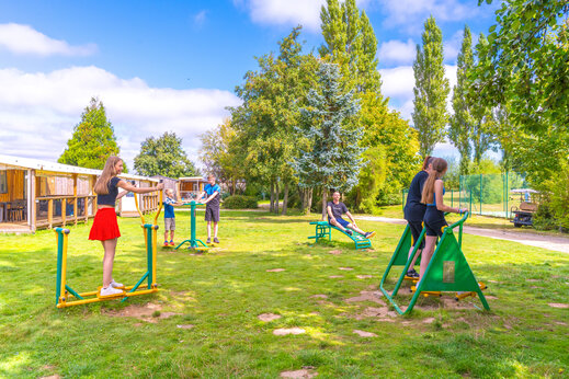 Familia usando equipos de fitness al aire libre en el camping CAPFUN Val d'Authie.