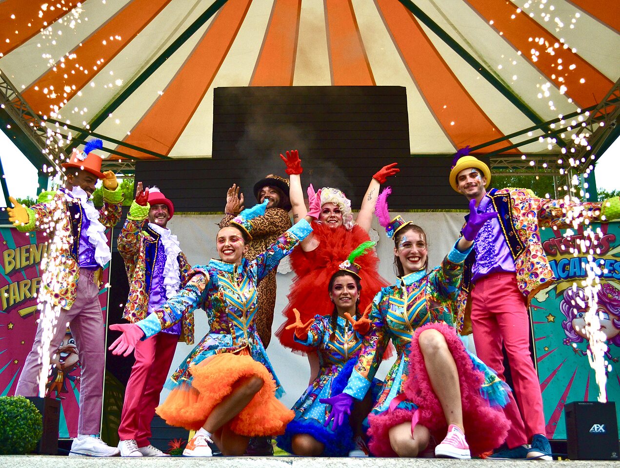 Artistas con disfraces coloridos y pirotecnia en el camping CAPFUN Vignes d'Or en Serignan.