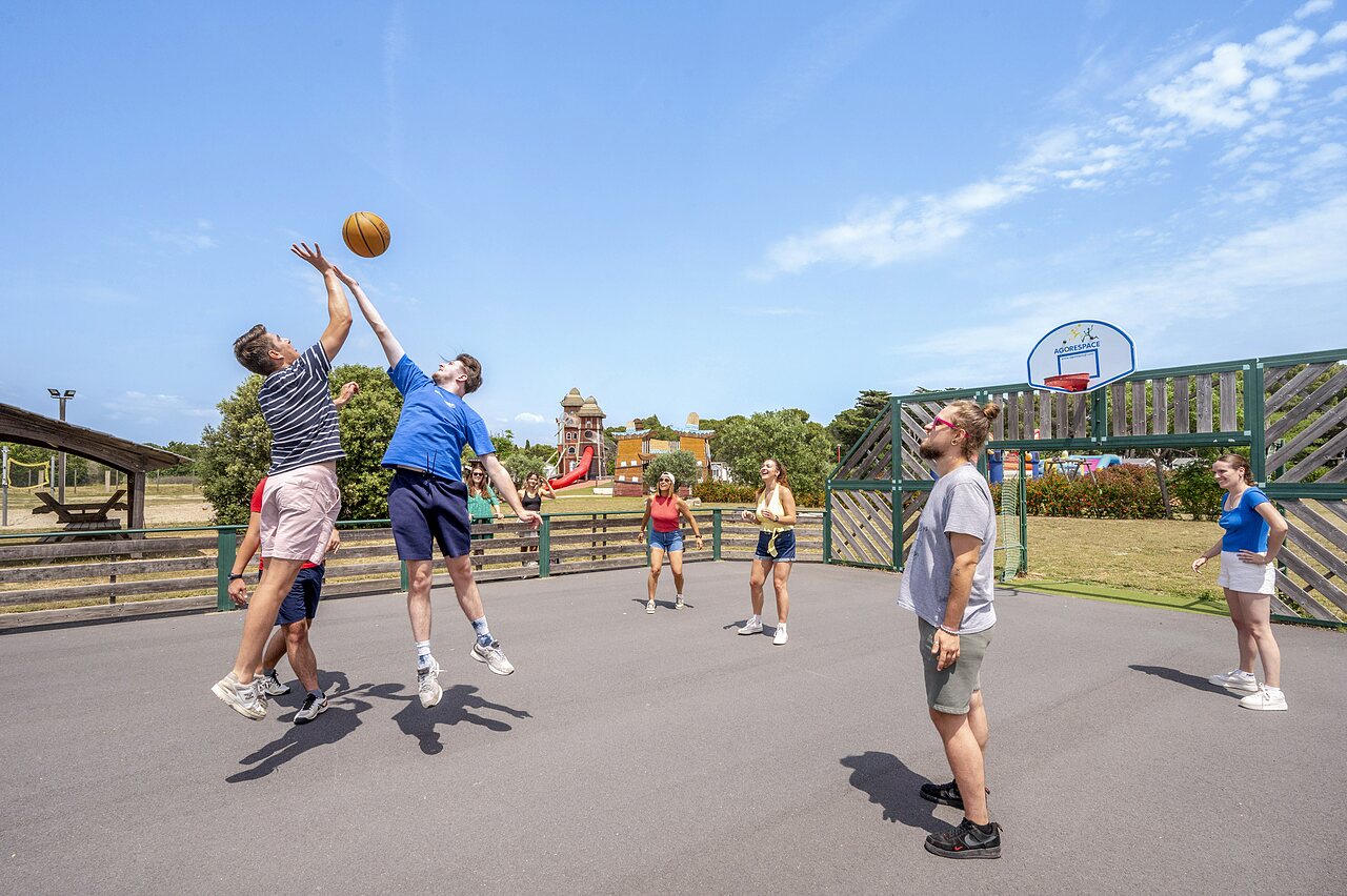 Pista multideporte con j�venes jugando baloncesto en el camping CAPFUN Vignes d'Or en Serignan.