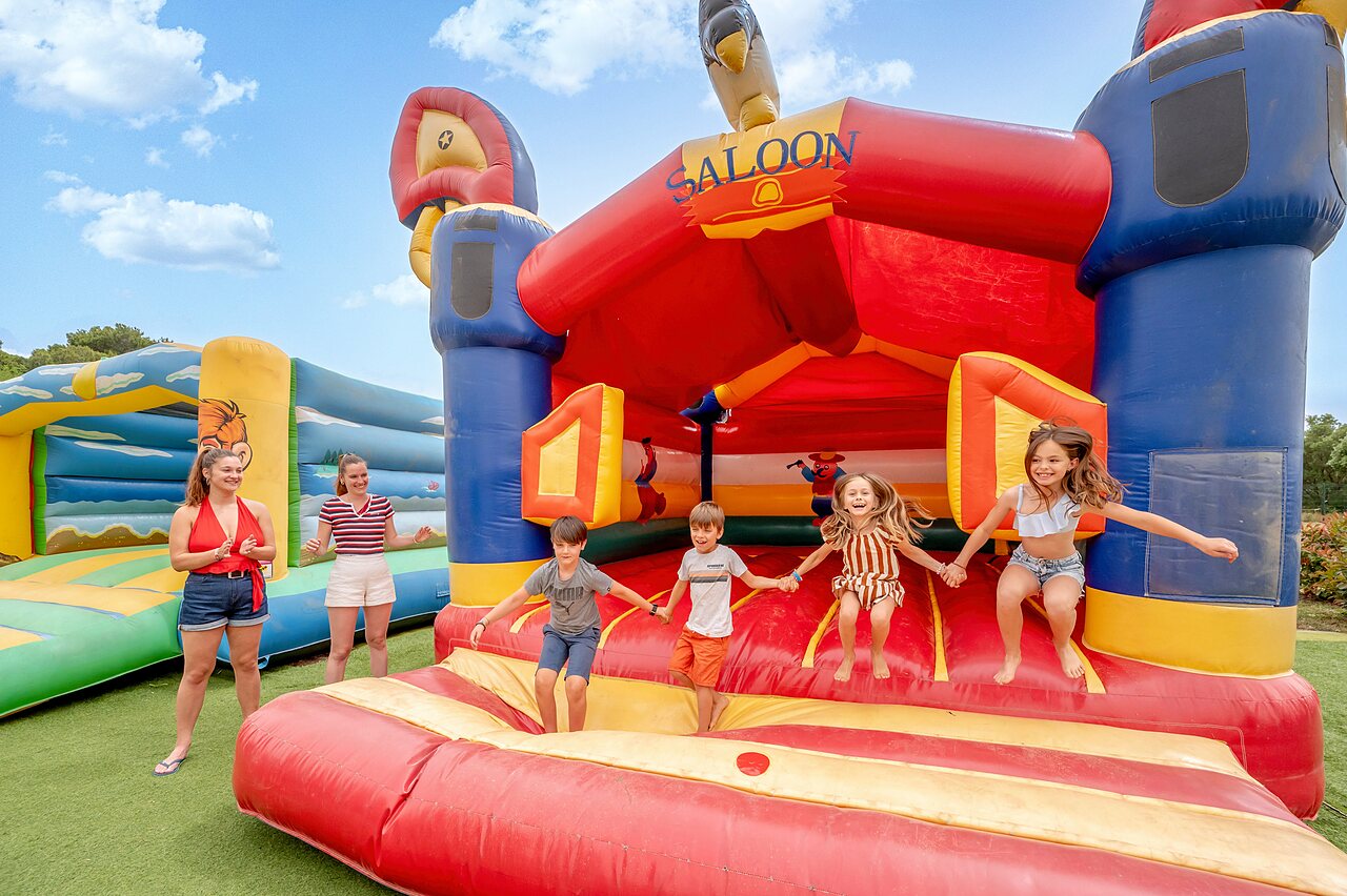 Ni�os saltando en estructura hinchable gigante Saloon en camping CAPFUN Vignes d'Or Serignan.