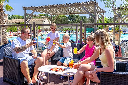 Familia en el bar de la piscina con bebidas, camping CAPFUN Vignes d'Or.