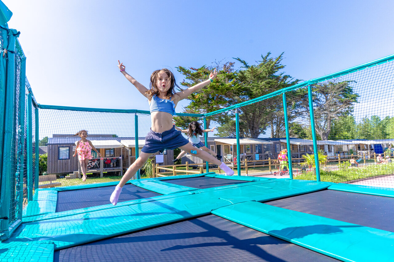 Ni�os saltando en trampolines, Mobil-homes al fondo en el camping CAPFUN Vikings en Saint Jean de la Rivi�re (50).