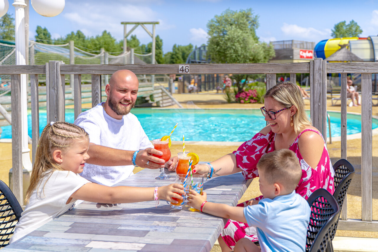 Familia con bebidas junto a la piscina del camping CAPFUN Vikings en Saint Jean de la Rivi�re (50).