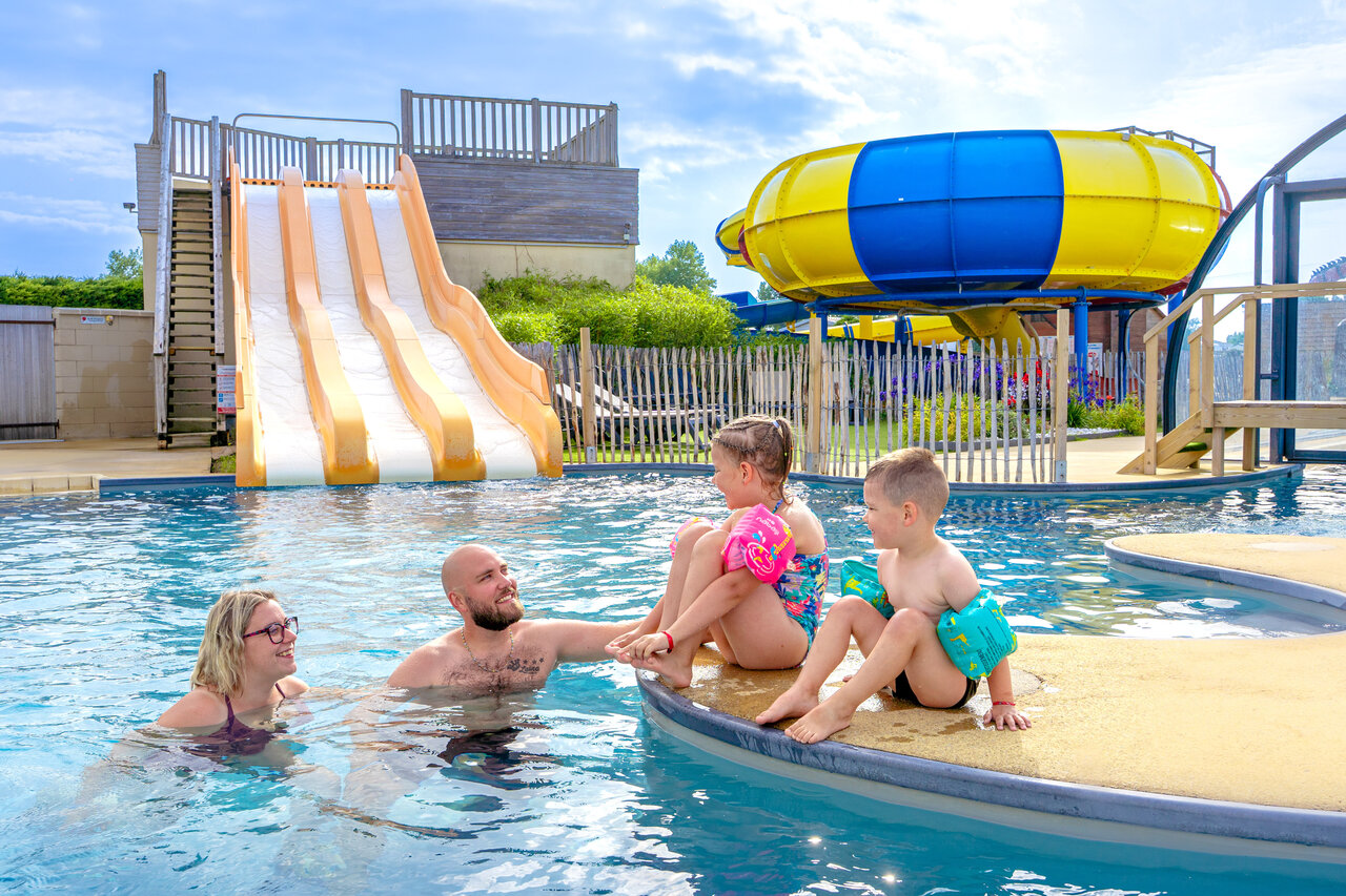Familia disfrutando de la piscina y toboganes en el camping CAPFUN Vikings en Saint Jean de la Rivi�re (50).