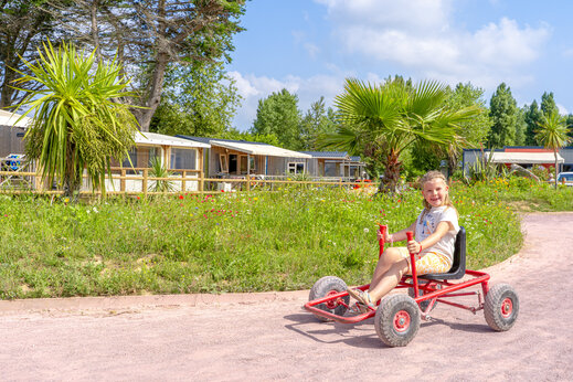 Ni�a sonriente en kart a pedales en el camping CAPFUN Vikings, Saint Jean de la Rivi�re (50).