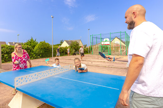 Familia jugando al ping-pong en mesa azul en el camping CAPFUN Vikings en Saint Jean de la Rivi�re (50).