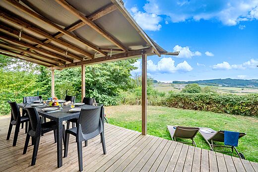 Terraza cubierta, mesa y vista panorámica en el camping CLICOCHIC Village des Meuniers en Dompierre-les-Ormes (71).