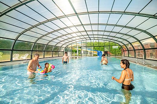 Piscina cubierta con familia y toboganes acuáticos en el camping CLICOCHIC Village des Meuniers.