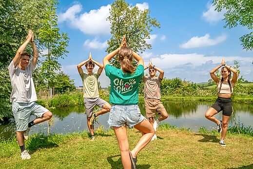 Yoga en grupo junto a un estanque en el camping CLICOCHIC Village des Meuniers (71).