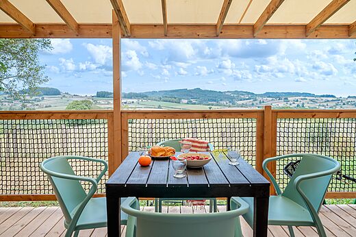 Terraza amueblada con mesa y vista panorámica en el camping CLICOCHIC Village des Meuniers en Dompierre-les-Ormes (71).
