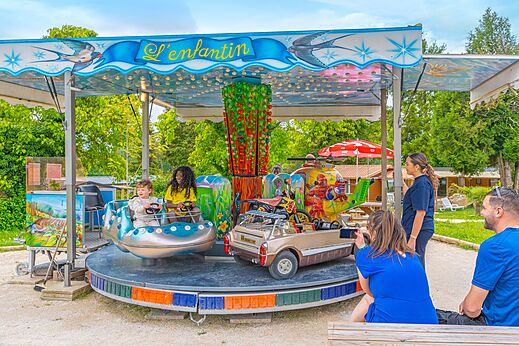 Carrusel infantil con coches y helicóptero en el camping CAPFUN Le Village Parisien.