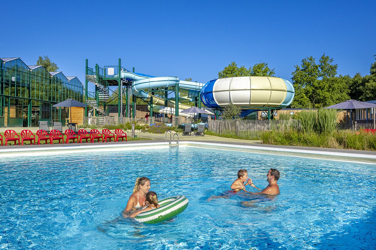 Familia disfrutando de la piscina exterior con toboganes en el camping CAPFUN Vlinderloo en Enschede.