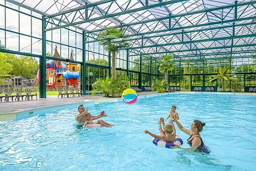 Piscina cubierta, familia jugando con balón, camping CAPFUN Vlinderloo en Enschede.