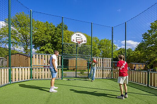 Cancha multideporte con canasta de baloncesto y jugadores en el camping CAPFUN Vlinderloo en Enschede.